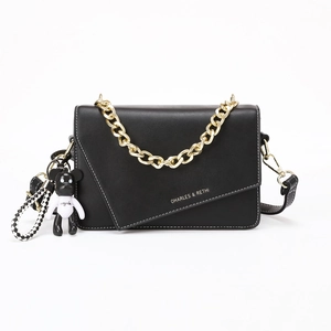 Black leather crossbody bag with white stitching and gold chain strap on white background
