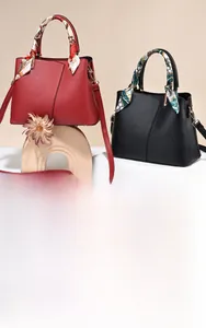 Detail of red and black lychee leather handbags with floral silk scarves on handles