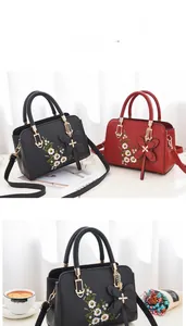 Close-up of elegant floral embroidery and butterfly pendant on soft leather handbags