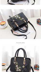 Detail of embroidered floral patterns on black soft leather tote bag with gold hardware