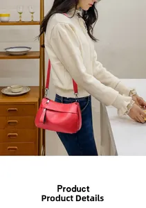 Detail of red pebbled leather crossbody bag with silver zipper and adjustable strap