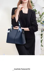 Detail of navy blue cowhide leather handbag with decorative scarf on handle and metal buckle