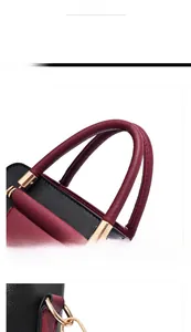 Gros plan sur le sac à main bicolore noir et bordeaux avec finitions métalliques dorées