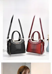 Detail of elegant crocodile-pattern leather handbags in black and wine red with metal clasps