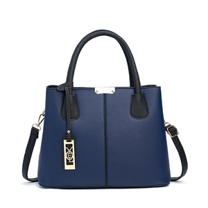 Sac à main en cuir bleu marine avec poignées noires et pendentif en métal doré