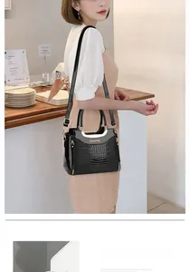 Close-up of black crocodile pattern handbag with gold logo and side zipper detail