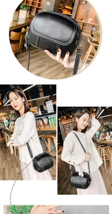 Detail of black pebbled leather crossbody camera bag with contrast white stitching