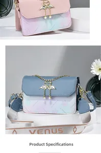 Detail of gradient crossbody bag with swan clasp and pearl pendant on a white platform