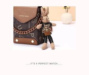 Detail of brown patterned crossbody bag with gold chain and a small bunny pendant charm