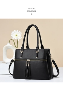 Detail view of black lychee texture tote bag with golden zippers and double tassel charms