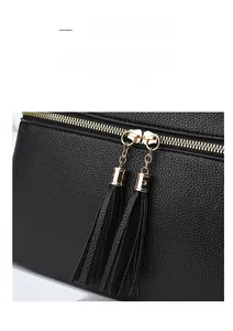 Detail of premium black lychee leather bag with dual golden zippers and long tassels