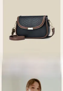 Detail of black pebbled leather crossbody bag with crocodile texture and gold clasp