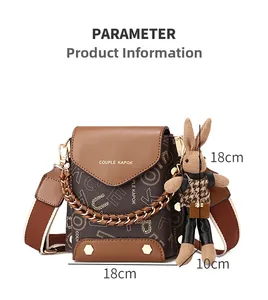 Close-up of brown crossbody bag featuring dual straps and a knitted bunny charm