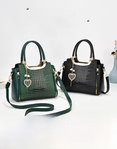 Detail of crocodile pattern handbags with gold handles and decorative heart pendants