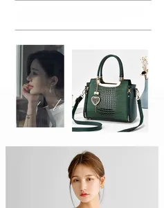 Detail of dark green crocodile embossed handbag featuring metal handles and heart pendant