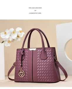 Detail of purple faux leather handbag with braided texture, gold charms and adjustable strap