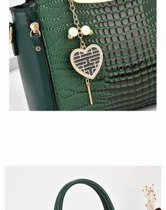 Detail of dark green crocodile pattern leather bag with pearl and heart pendant
