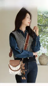 Model wearing a stylish cream crossbody bag with brown leather flap and mascot charm