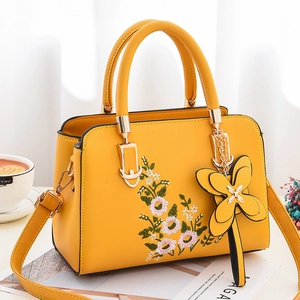 Yellow faux leather tote bag with elegant floral embroidery and flower charm