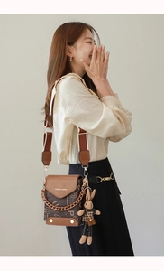 Detail of vintage crossbody bag with brown monogram pattern, wide strap and rabbit charm