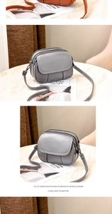 Close-up of gray pebble leather crossbody bag with three zipper compartments