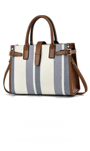 Close-up of blue and white striped canvas tote bag with brown leather trim and gold buckle