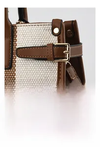 Detail of brown lychee grain leather stitching and beige woven fabric with gold buckle