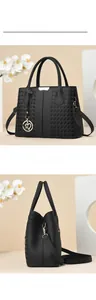 Detail of black pebbled leather tote with woven texture and gold heart charm