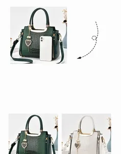 Detail view of crocodile embossed leather tote with metal handles and heart charm