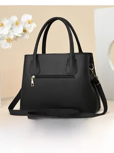 Detail view of the back of a black textured leather handbag with a gold zipper pocket