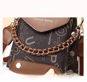 Detail view of printed leather bag with gold chain strap and bottom metal rivets