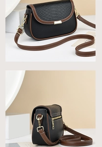 Detail view of the black and brown leather crossbody bag with crocodile embossed pattern