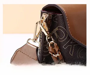 Close-up of golden metal clasp and chain detail on stylish brown printed crossbody bag