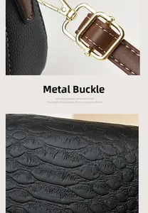 Close-up of black crocodile texture leather bag with gold hardware and brown shoulder strap