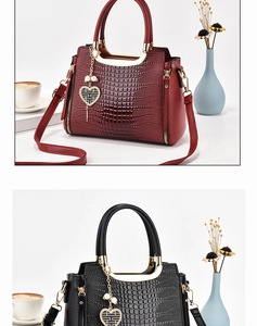 Detail of crocodile pattern leather handbag with gold metal rings and heart charm
