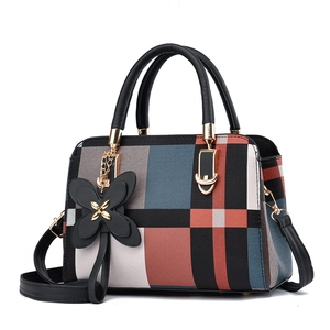 Handtasche mit Karomuster, Schmetterling-Anhänger und goldenen Details in 45-Grad-Ansicht