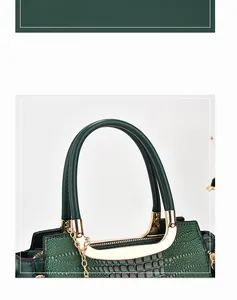 Detail of dark green embossed leather handbag with elegant gold metal handle and chain