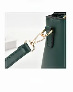 Detailed close-up of premium golden metal buckle and green leather strap on women's bag