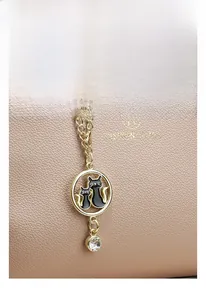 Detail view of gold-plated cat charm with zircons on pink lychee grain leather bag