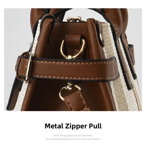 Detailed close-up of golden metal zipper and striped fabric on brown leather bag