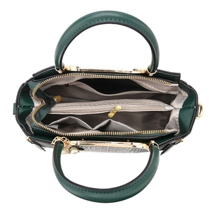 Dark green handbag with multi-compartment interior and gold hardware from a top-down view