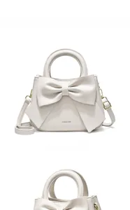 Macro detail of creamy white handbag showing top handles and decorative oversized bow