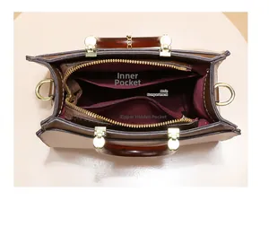 Internal view of a leather handbag featuring a red lining, main pocket, and zipper pocket