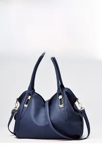 Detail view of deep blue leather handbag with pebble texture and gold tone metal accents