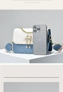 Detail of white and blue crossbody bag with gold swan lock and pearl embellishments