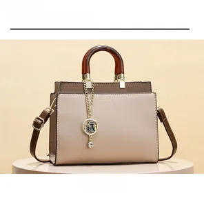 Detail of color-block leather handbag featuring amber handle and cat charm on a display