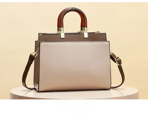 Detail of contrast stitching and amber-textured handle on litchi grain leather handbag