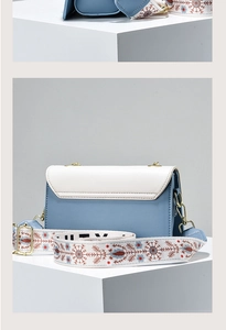 Detail of blue and white crossbody bag with floral jacquard strap and gold hardware