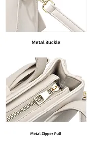 Close-up of golden metal zipper and detachable strap buckle on beige handbag