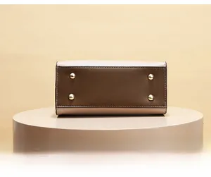 Detail of two-tone handbag base with four gold metal protective feet on a beige leather texture
